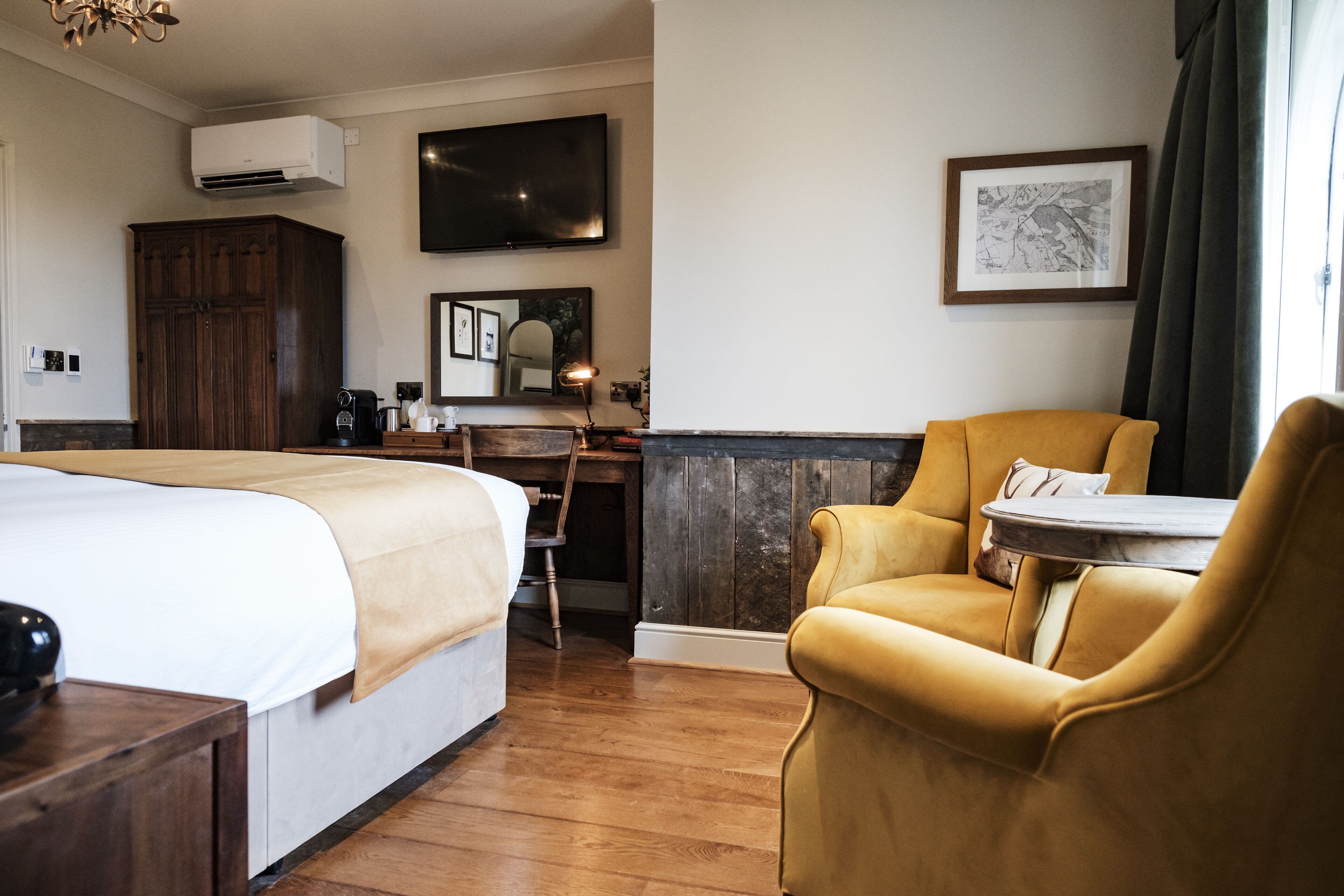 A hotel room with a large bed, a desk with a chair, a television, and a framed picture on the wall.