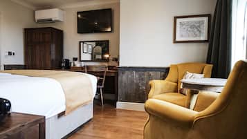 A hotel room with a large bed, a desk with a chair, a television, and a framed picture on the wall.