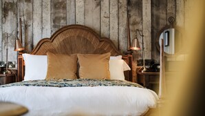 Uma cama com cabeceira de madeira, duas luminárias de cabeceira e um espelho na parede.
