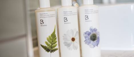 Three bottles of hand wash and body lotion with floral designs.