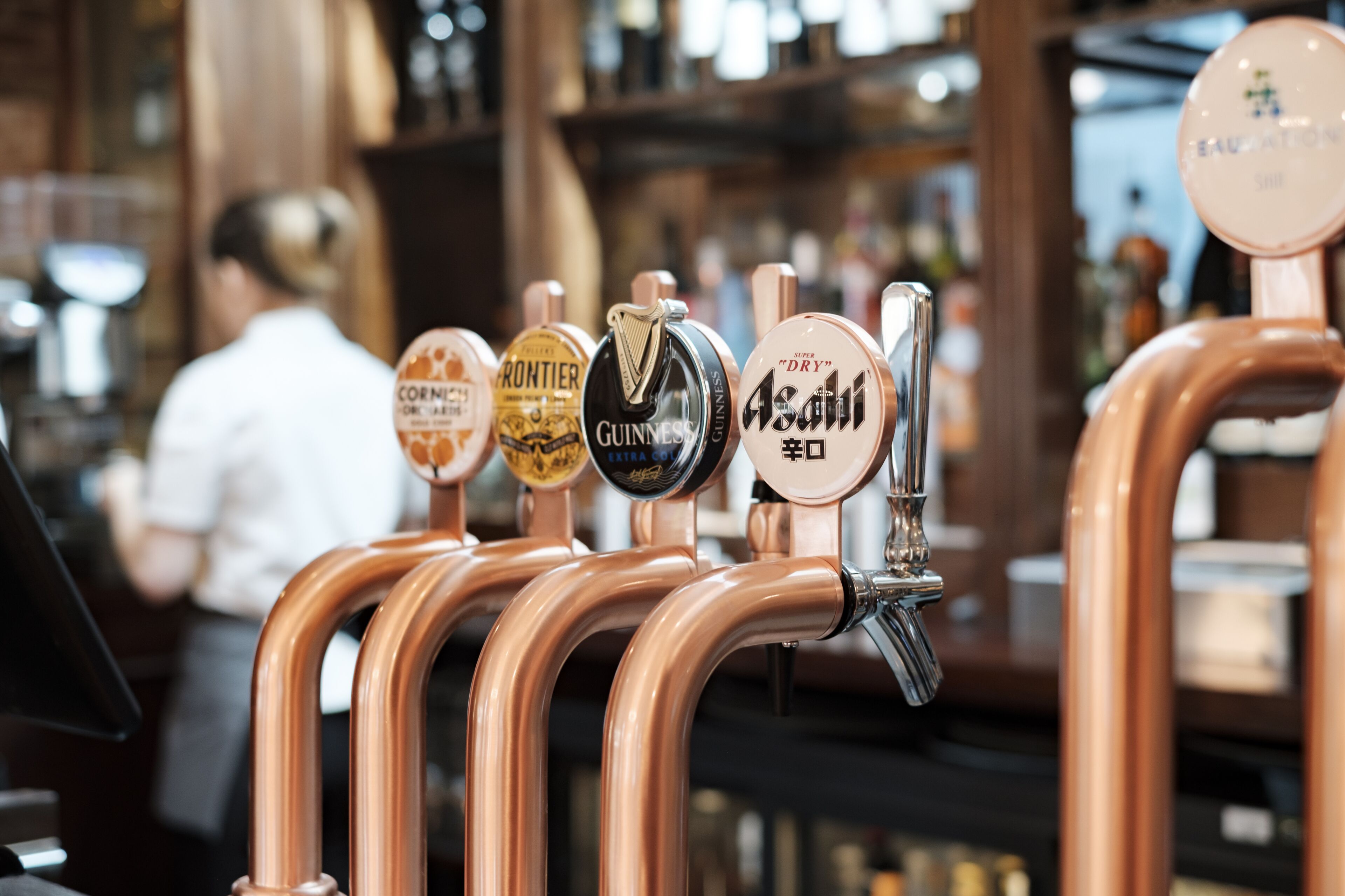 Eine Reihe von Zapfhähnen für Bier, mit Beschriftungen für Marken wie Guinness und Asahi.