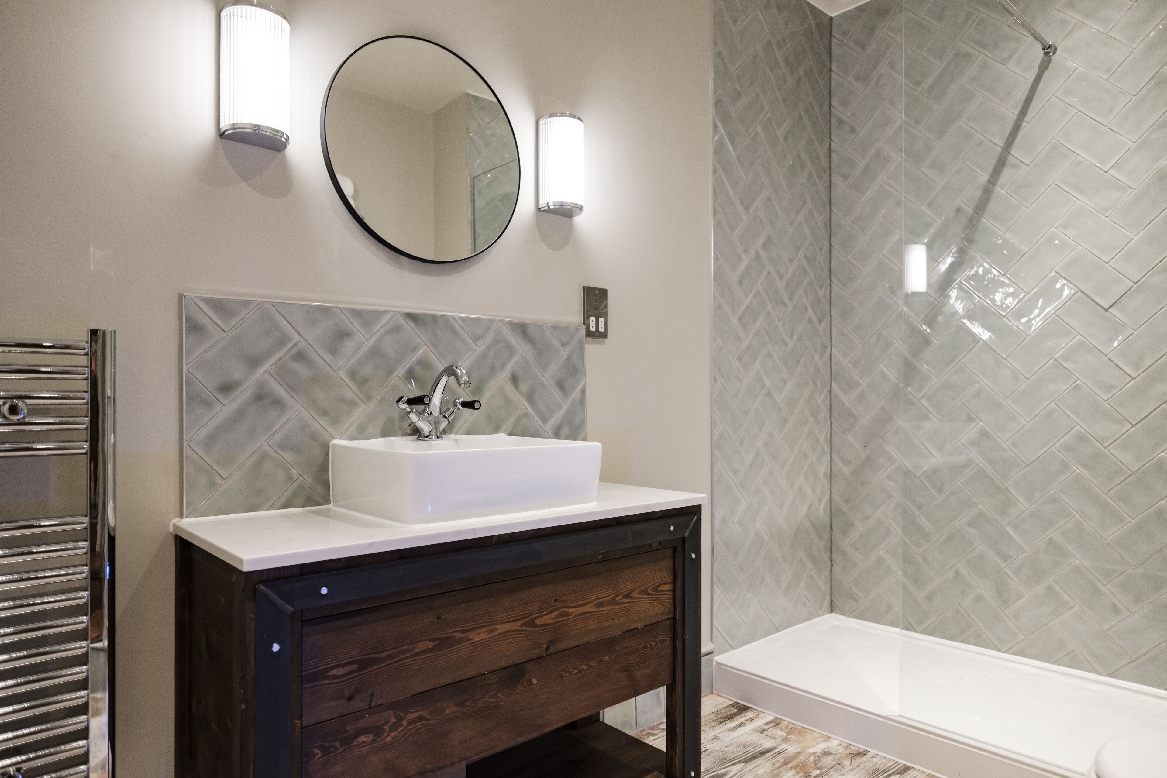 A bathroom with a white sink, a mirror, and a shower.