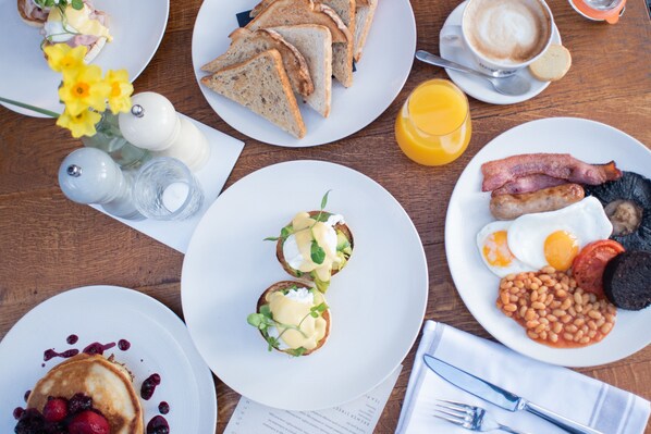 A breakfast table with various dishes including toast, eggs, sausages, and pancakes.