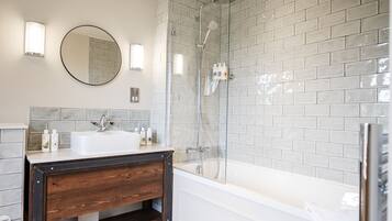 Un baño moderno con ducha de vidrio, lavamanos blanco y tocador de madera.