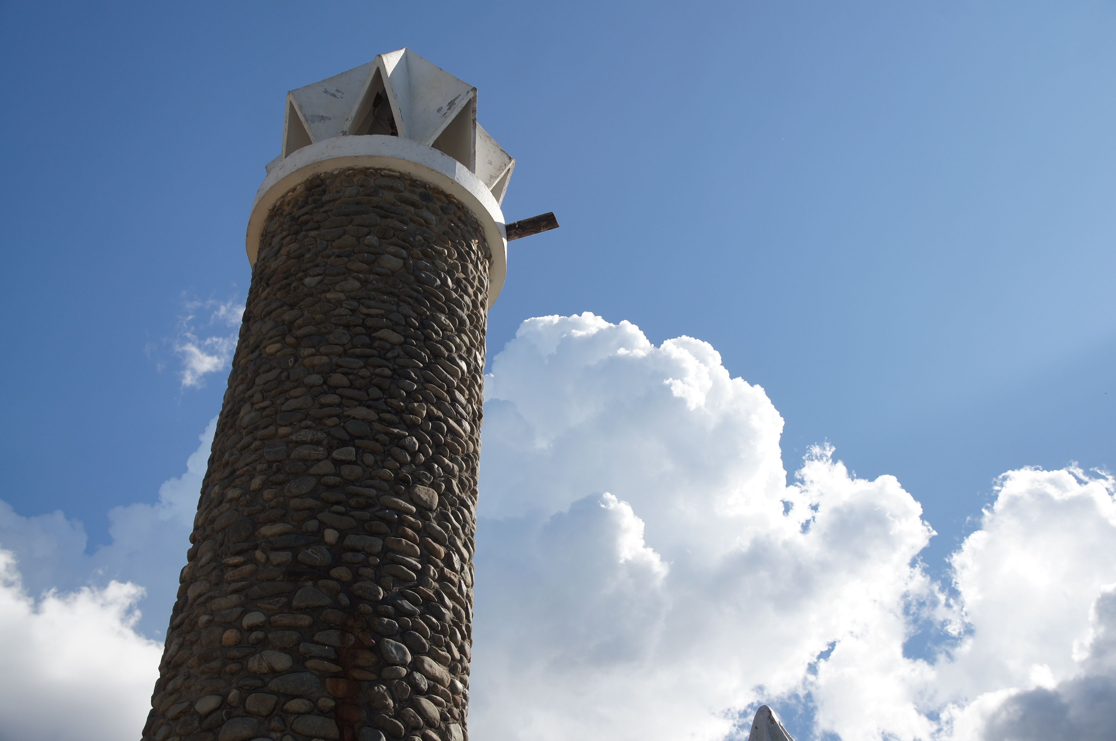 A stone tower with a metal spire against a clear sky.