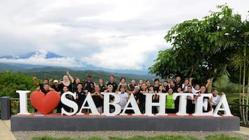 Een groep mensen poseert voor een bord met de tekst 'I love Sabah Tea' en een groot rood hart.
