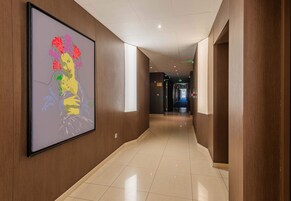 A hallway with a large framed artwork on the wall, wooden paneling, and a shiny tiled floor.
