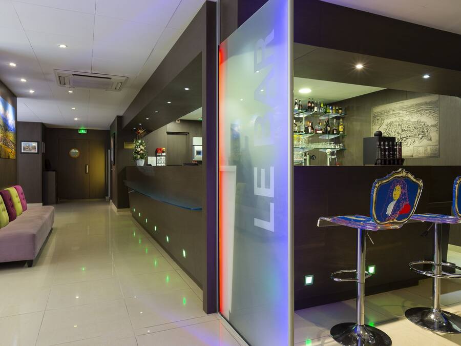 A modern hotel lobby with a reception desk, bar area, and seating.