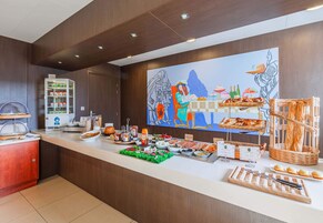 Un mostrador de buffet con diferentes opciones de comida, un refrigerador y un cuadro en la pared.