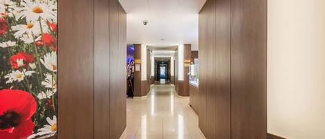 Een hotelgang met houten lambrisering, een betegelde vloer en een beveiligingscamera aan het plafond.