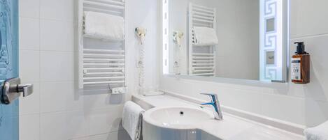 A modern bathroom with a white sink, a mirror, and two towel racks.