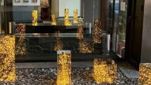 A modern interior with a glass partition, decorative light fixtures, and a stone pathway. - Hotel Concorde (Arona)