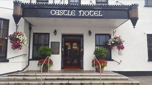 El exterior del Castle Hotel con un cartel sobre la entrada, plantas en macetas y una escalera que sube hacia la puerta.