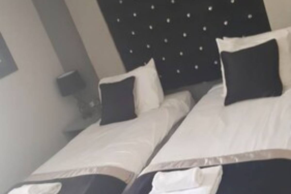 A hotel room with two beds, a black headboard, white bedding, and a patterned floor.