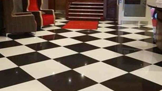 Un vestíbulo con piso a cuadros, una escalera y un candelabro.
