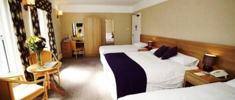 A hotel room with two beds, a desk, a chair, and a mirror.