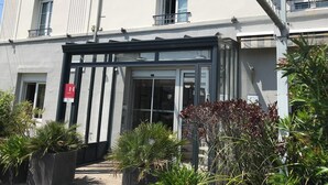A hotel entrance with a glass door, a sign reading "Le Surcouf", and a red "H" sign indicating a hotel. - Brit Hotel Le Surcouf (Saint-Malo)
