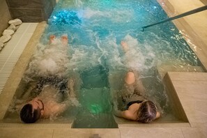 Two people relaxing in a hot tub with a clear view of the water and a tiled floor. - Lory (Chianciano Terme)