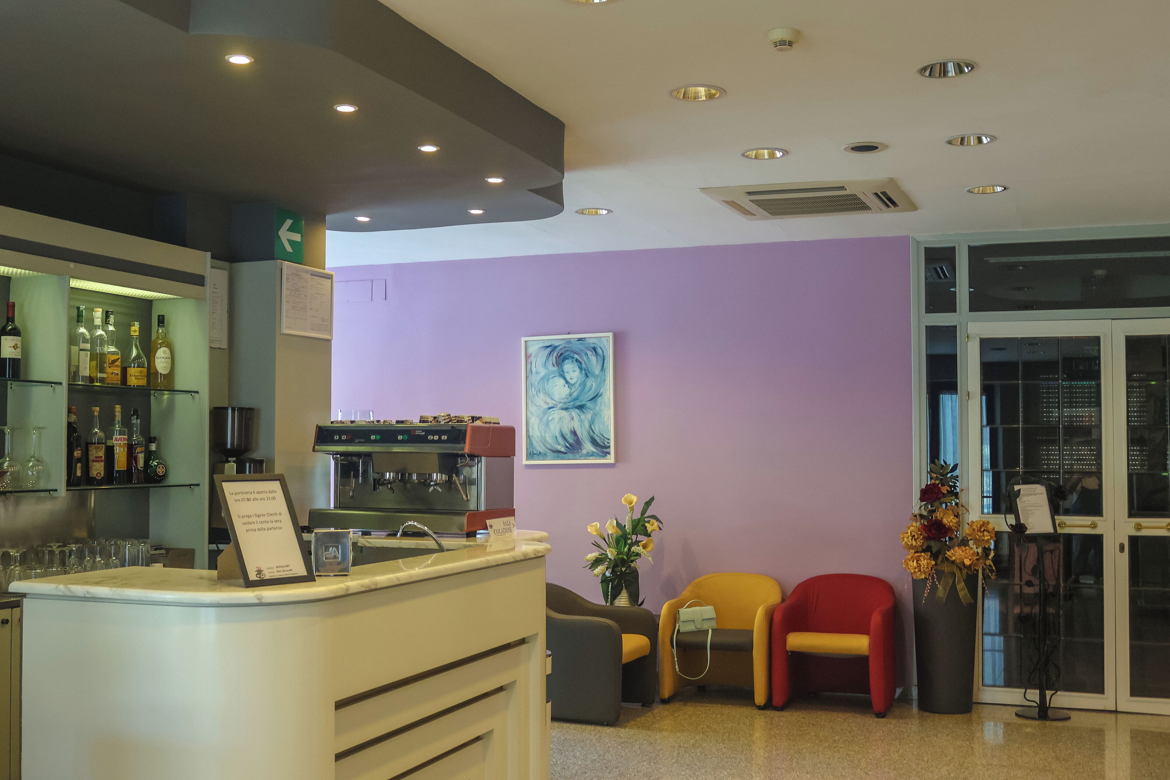 A bar area with a counter, seating, and a wall with a painting.
