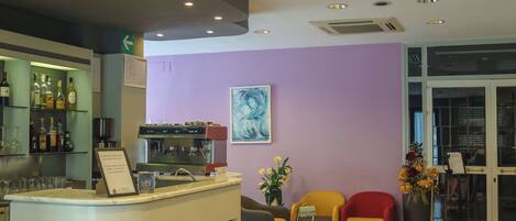 A bar area with a counter, seating, and a wall with a painting.