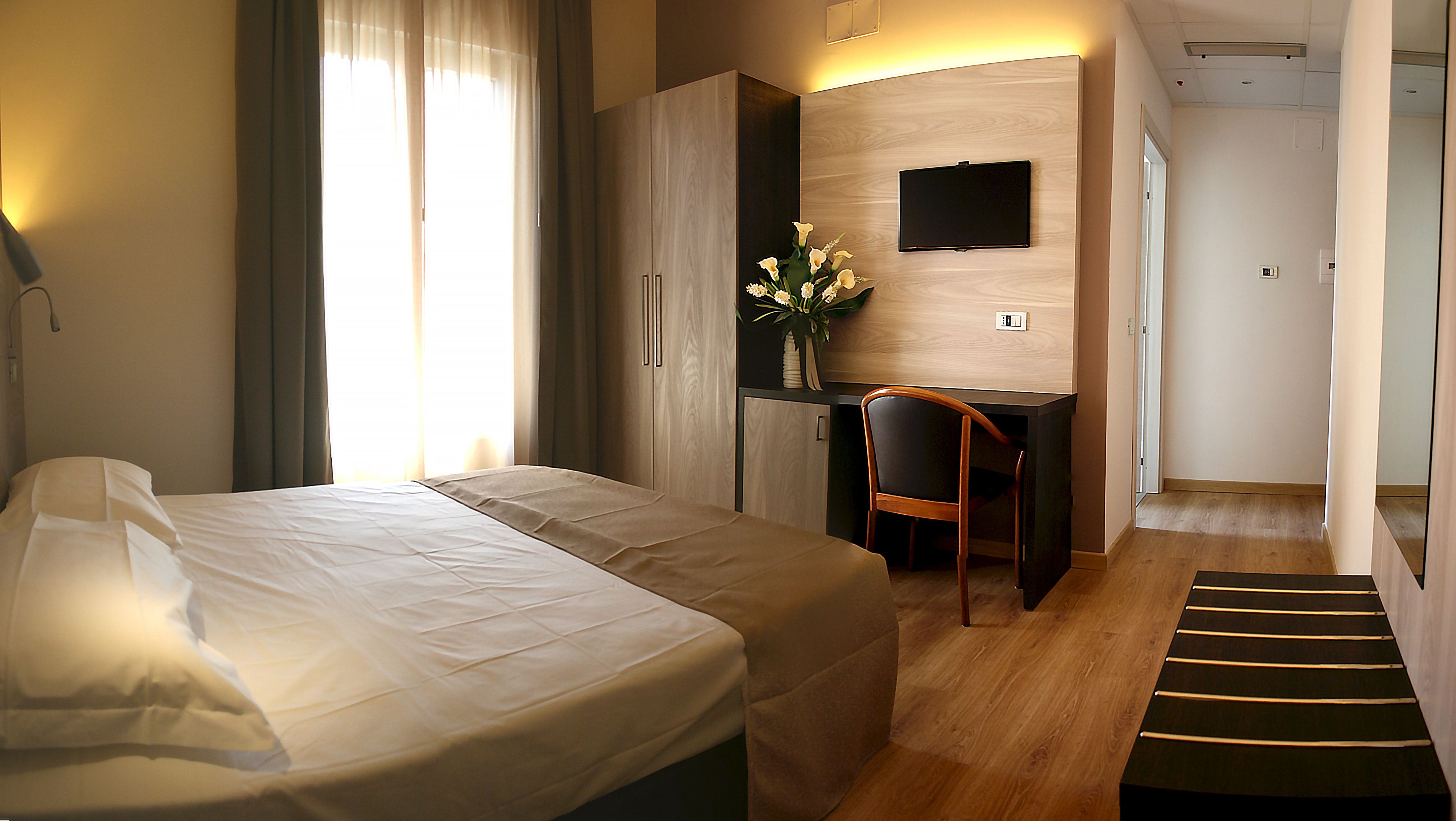 Una habitación de hotel con cama, escritorio, silla y televisor.