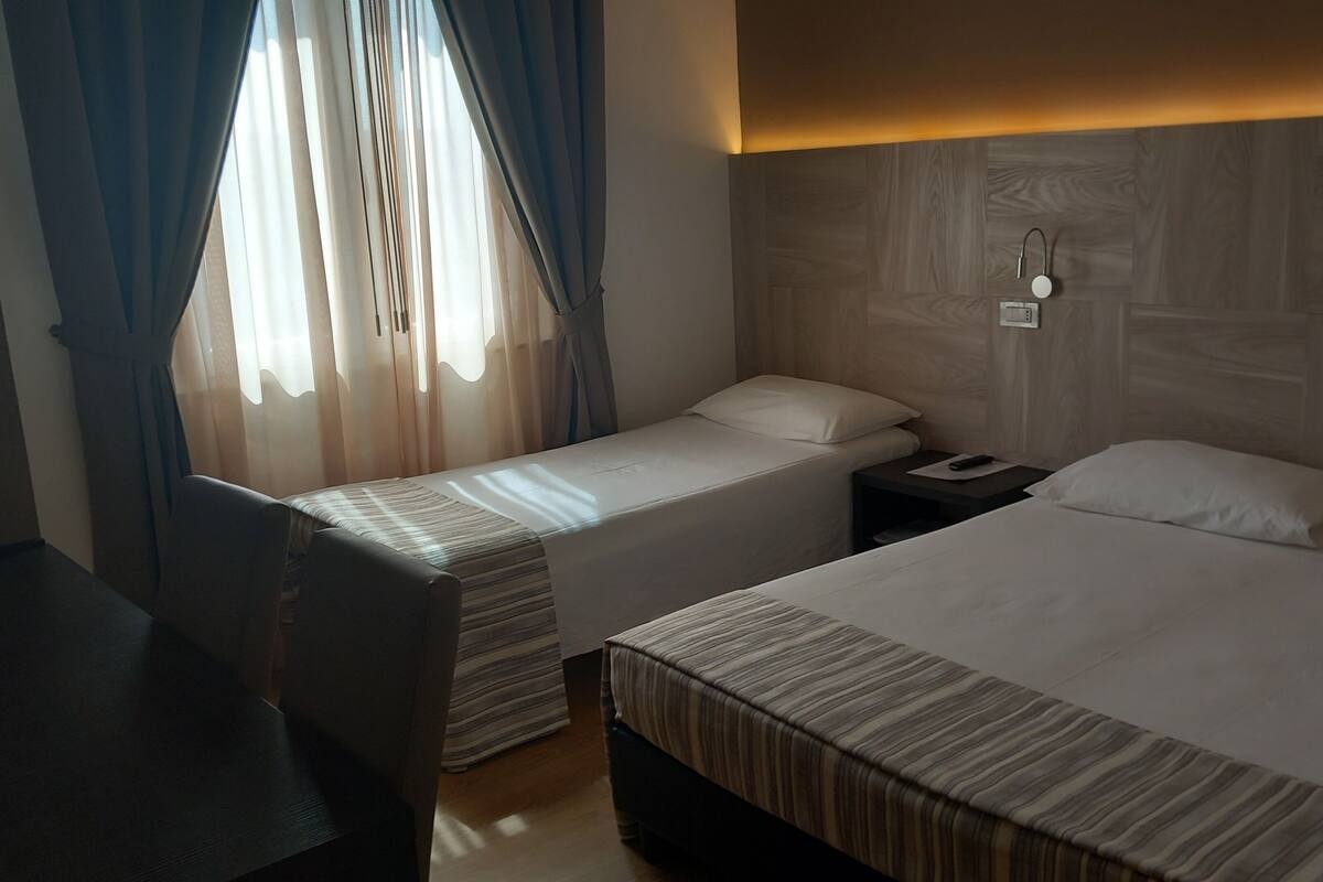 A hotel room with two beds, a desk, and a nightstand.