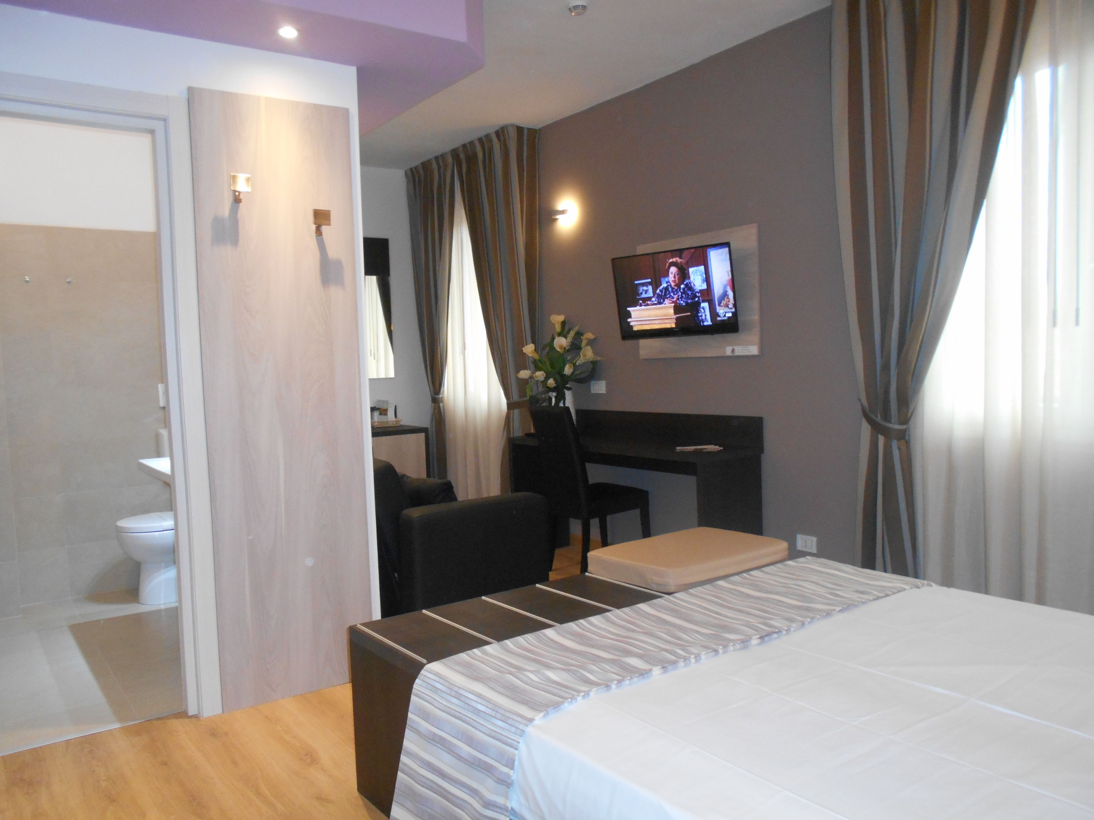 Une chambre d’hôtel comprenant un lit, un bureau, une chaise, une télévision et une salle de bain.