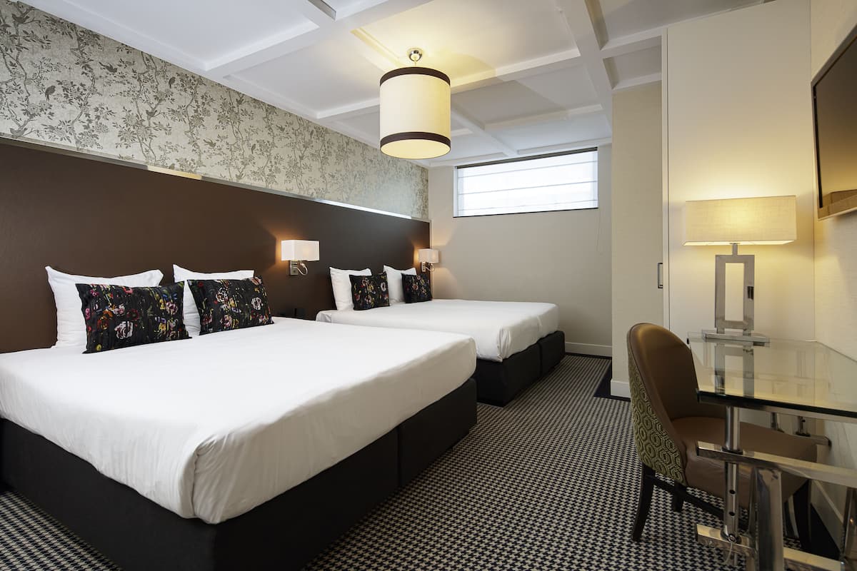 A hotel room with two beds, a desk, and a chair.
