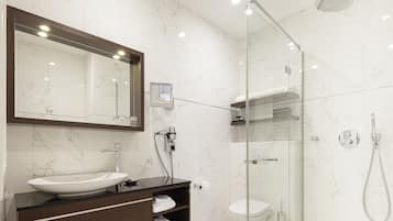 A modern bathroom with a marble sink, a glass-enclosed shower, and a large mirror.