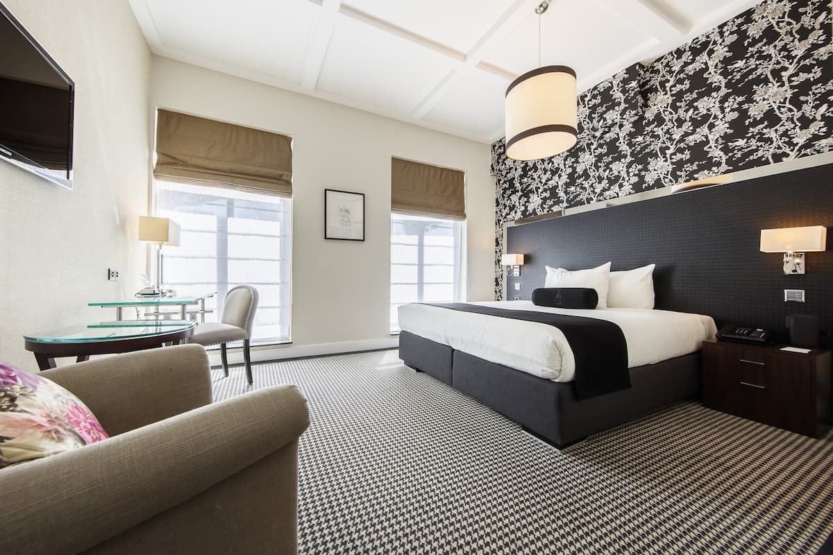 A hotel room with a large bed, a desk, a chair, and a television.