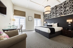 Une chambre d’hôtel avec un grand lit, un bureau, une chaise et un téléviseur.