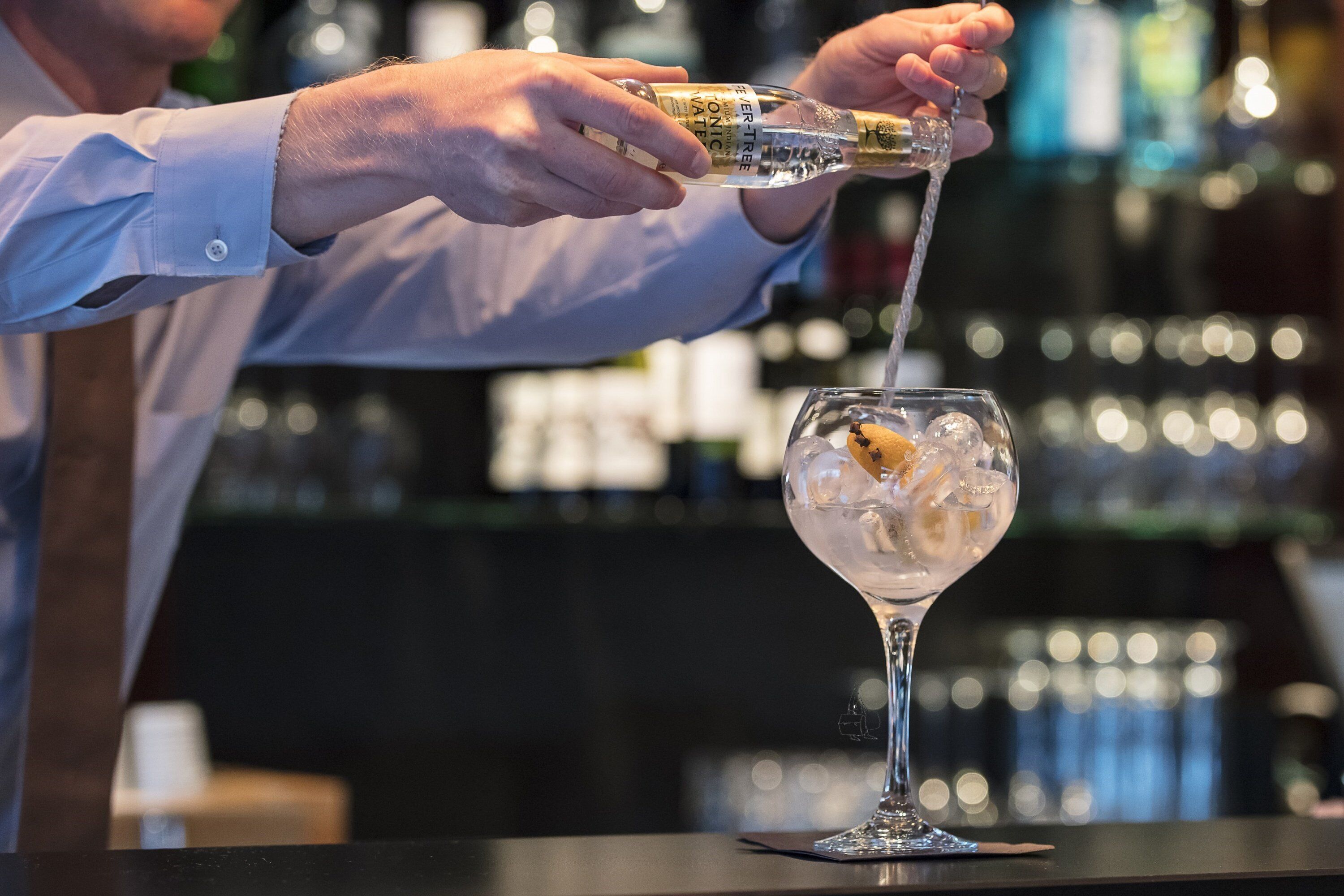 A bartender pouring a drink into a glass.