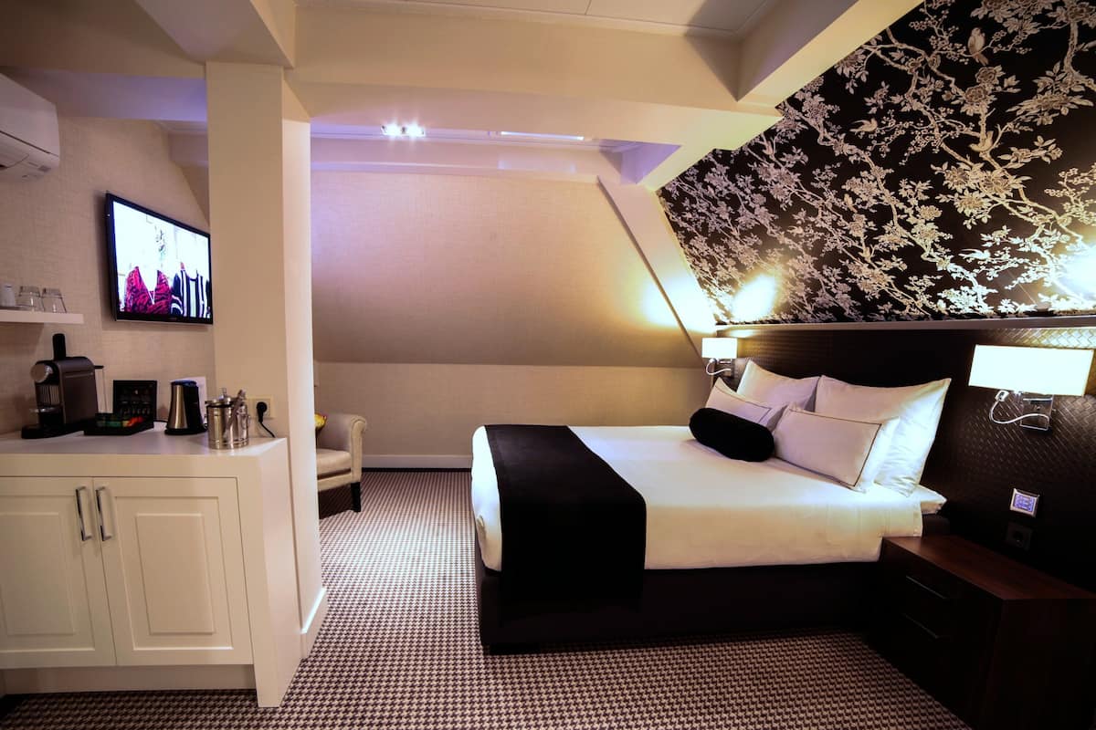 A hotel room with a bed, a TV, a desk, and a cabinet.