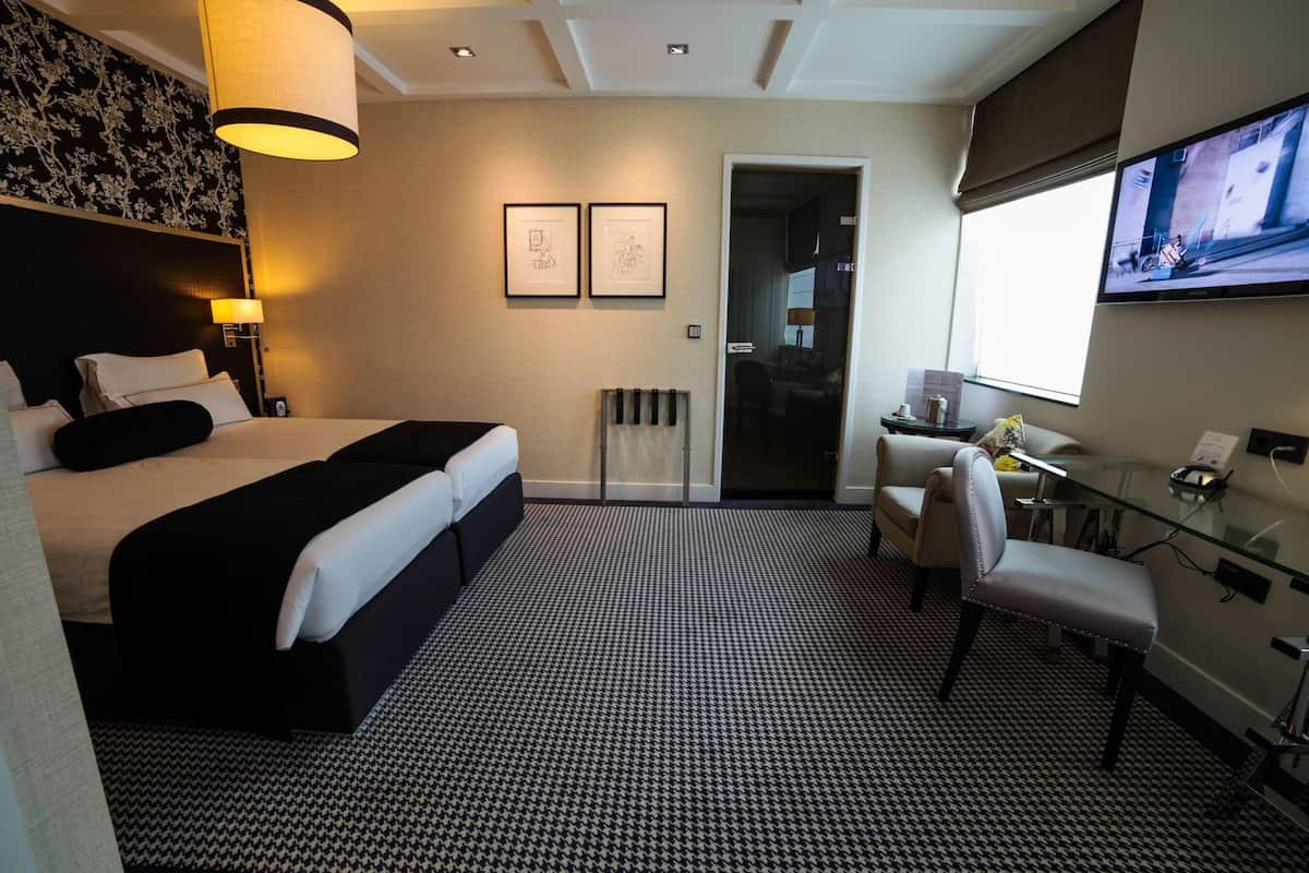 A hotel room with a bed, desk, chair, and a TV.