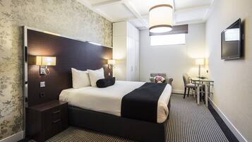 A hotel room with a large bed, bedside tables, a desk, and a chair.