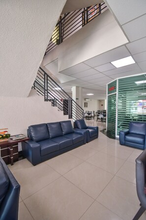 Eine moderne Lobby mit einer Treppe, einem blauen Ledersofa und einer Glaswand mit Namensschild.