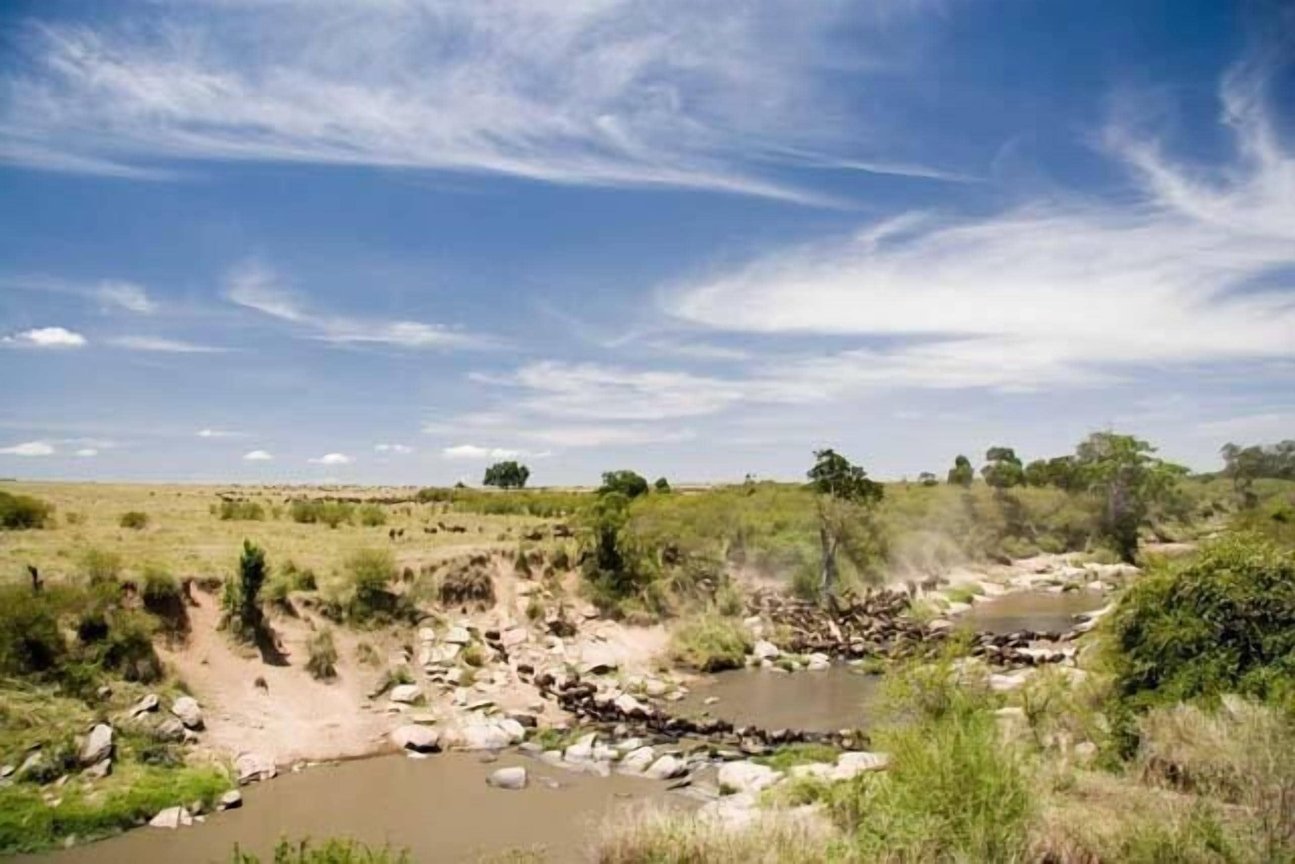 A natural landscape with a river, rocks, and sparse vegetation.