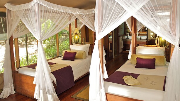 A room with two beds, each with a canopy. The room has wooden flooring and large windows. - Mara Intrepids Tented Camp (Maasai Mara)