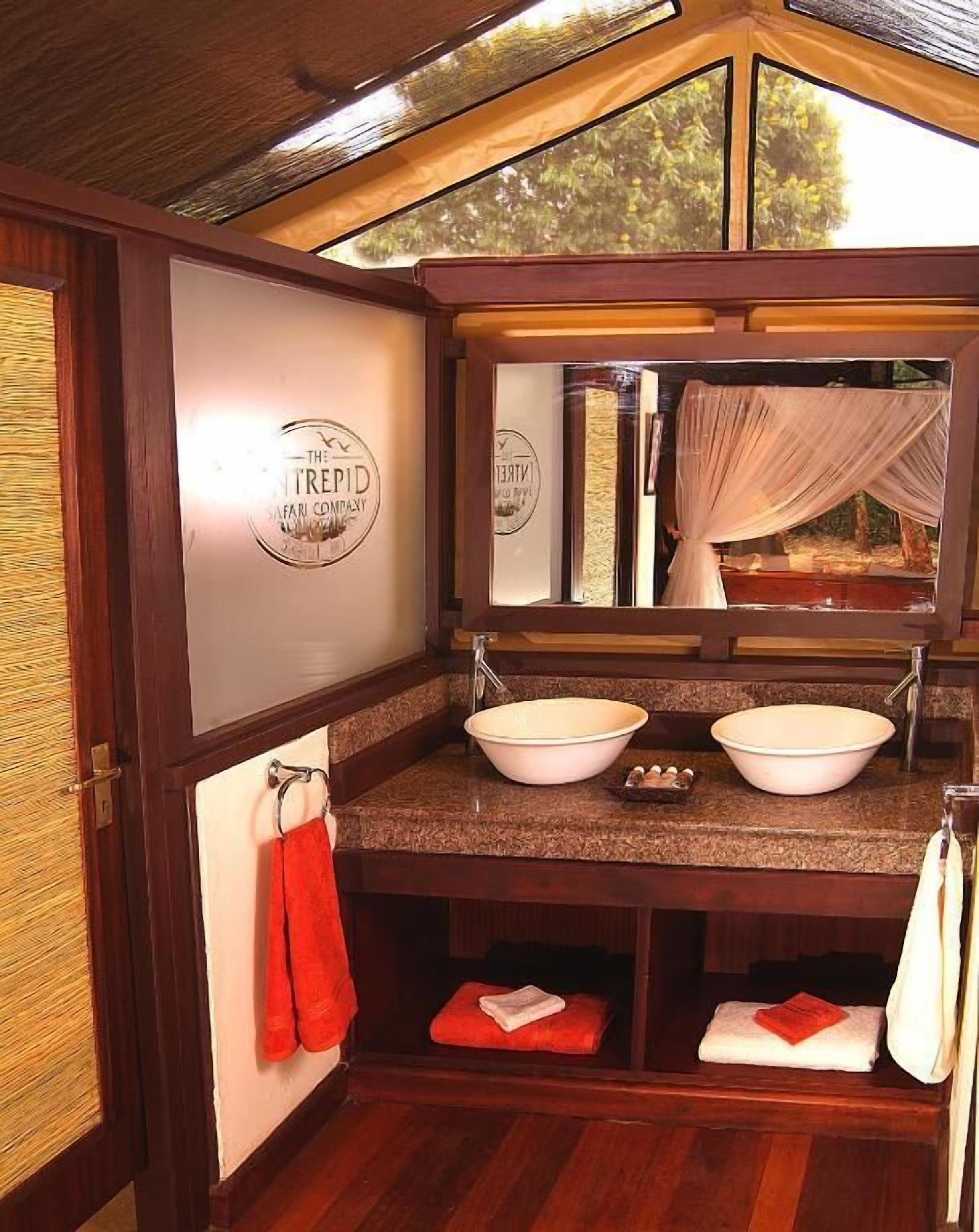 Un baño con tocador de madera, dos lavamanos, un espejo y un perchero para toallas.