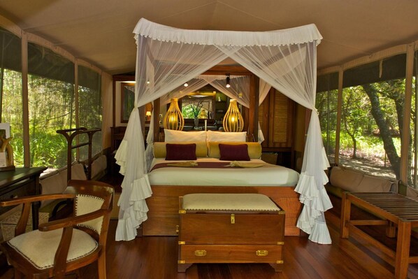 A four-poster canopy bed with a wooden headboard, a bedside table, and a bench.