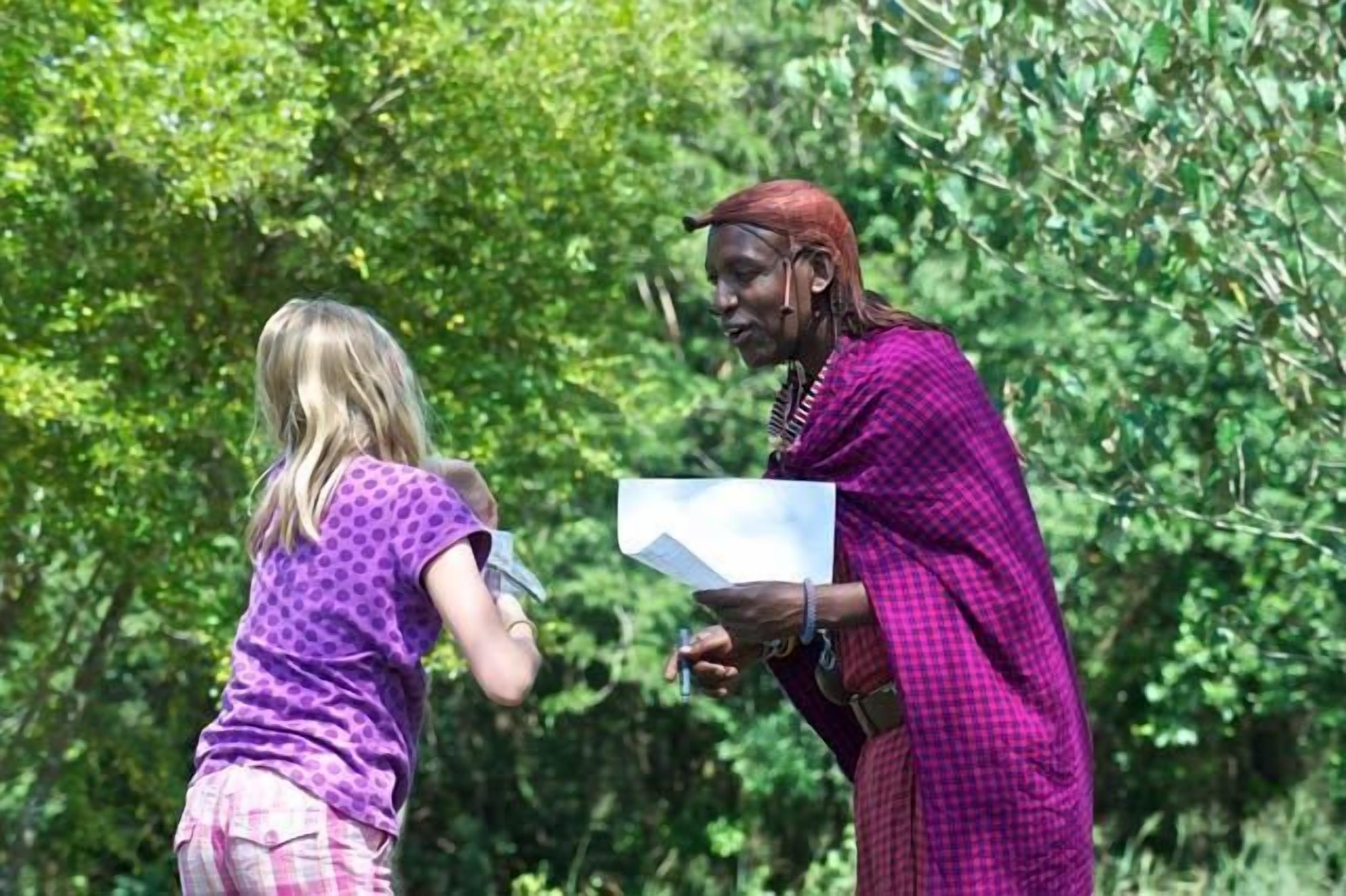 Two people in a natural setting, one holding a piece of paper.