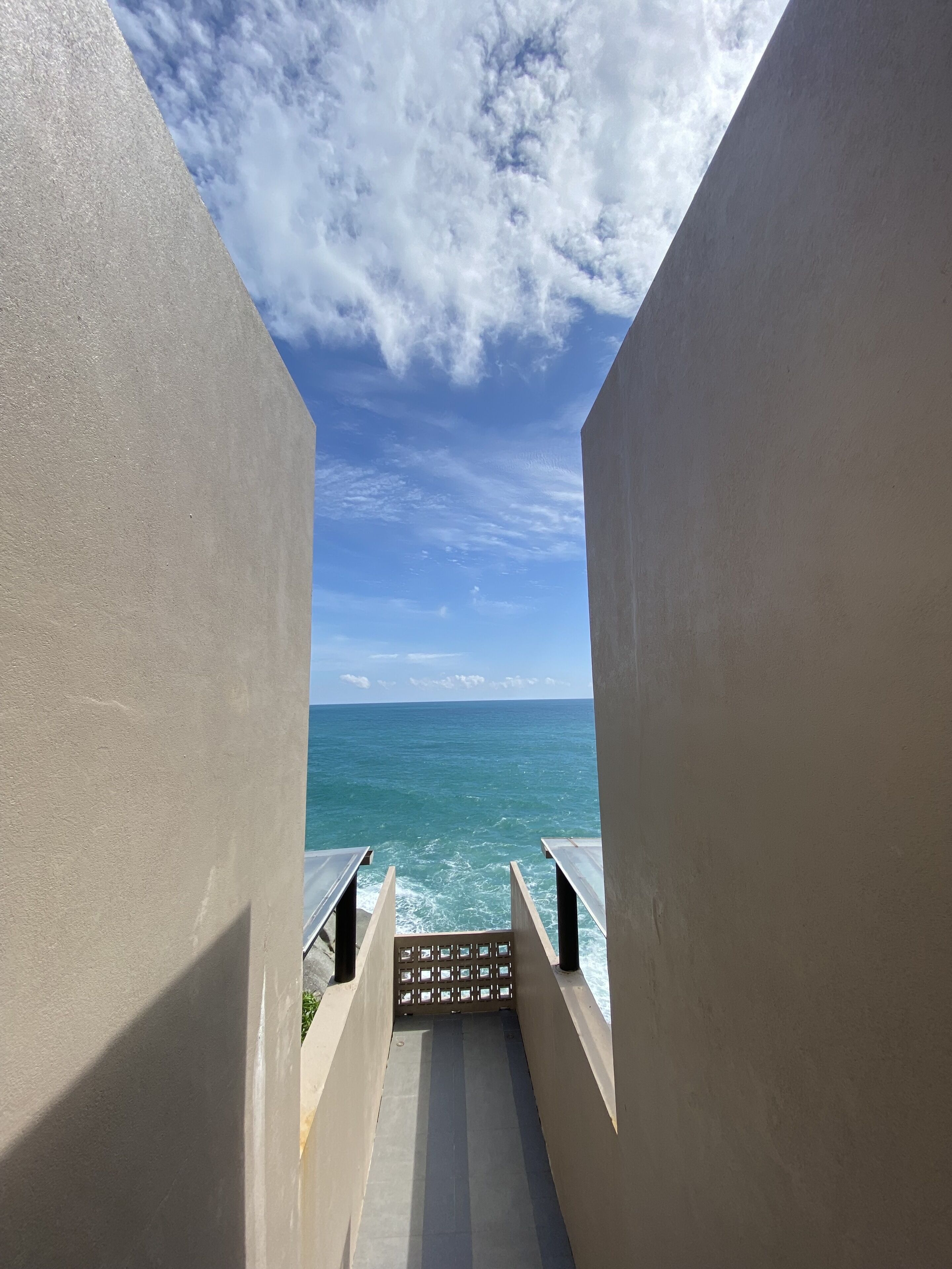 A corridor leading to a balcony with a view of the ocean.