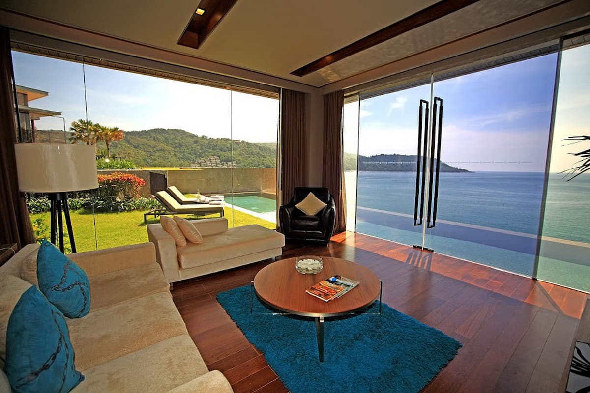 A modern living room with a large window, a sofa, a coffee table, and a chair.