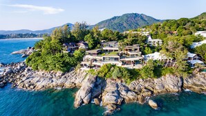 A coastal property with multiple modern houses, rocky shoreline, and a mountain in the background. - Impiana Private Villas Kata Noi (Karon)