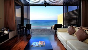 A modern living room with a view of the ocean, a wooden coffee table, and a sofa with cushions. - Impiana Private Villas Kata Noi (Karon)