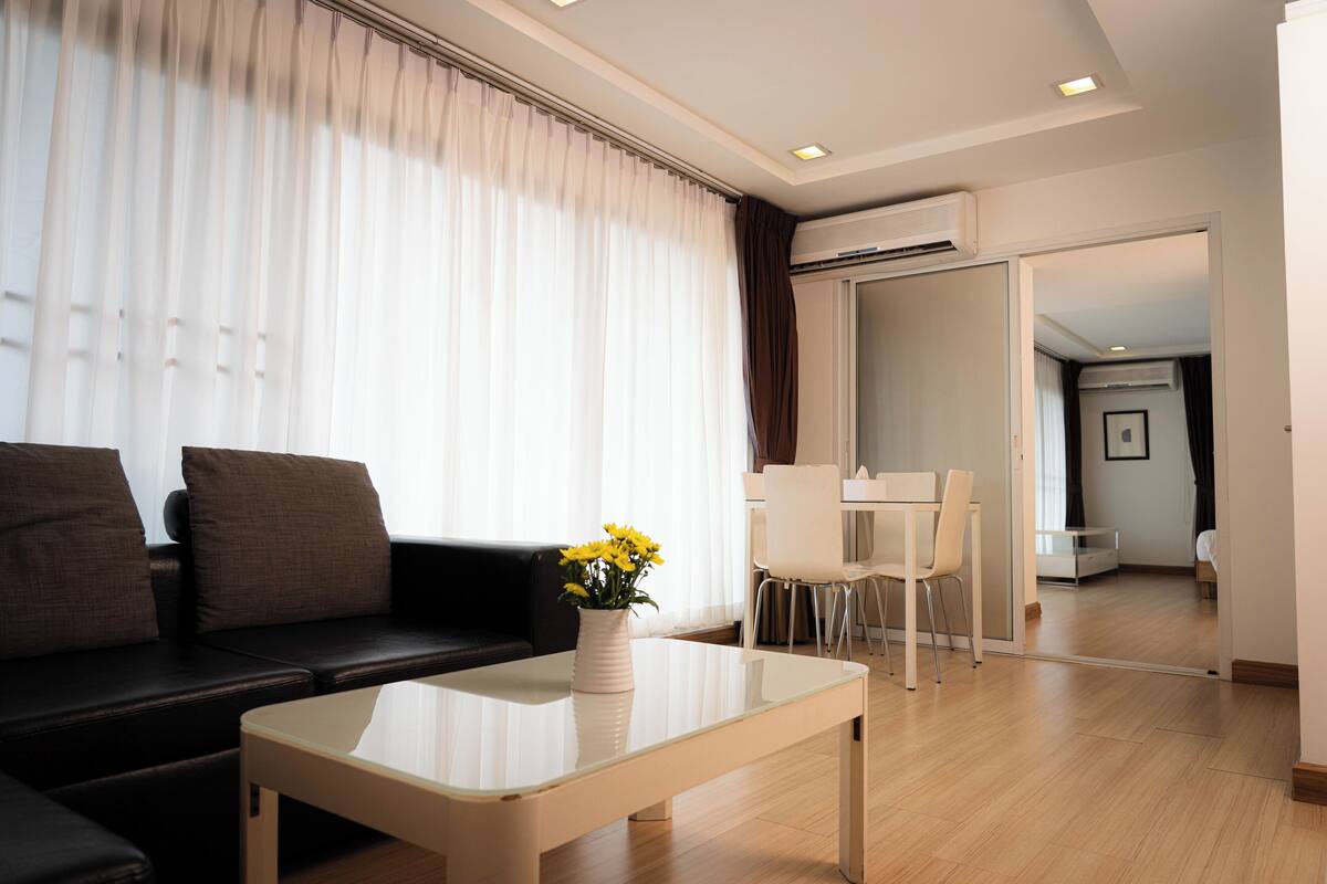 A modern living room with a sofa, a coffee table, and a dining area.