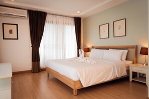 A neatly made bed with white linens, a wooden headboard, and two bedside lamps. - Baan K Residence (Bangkok)