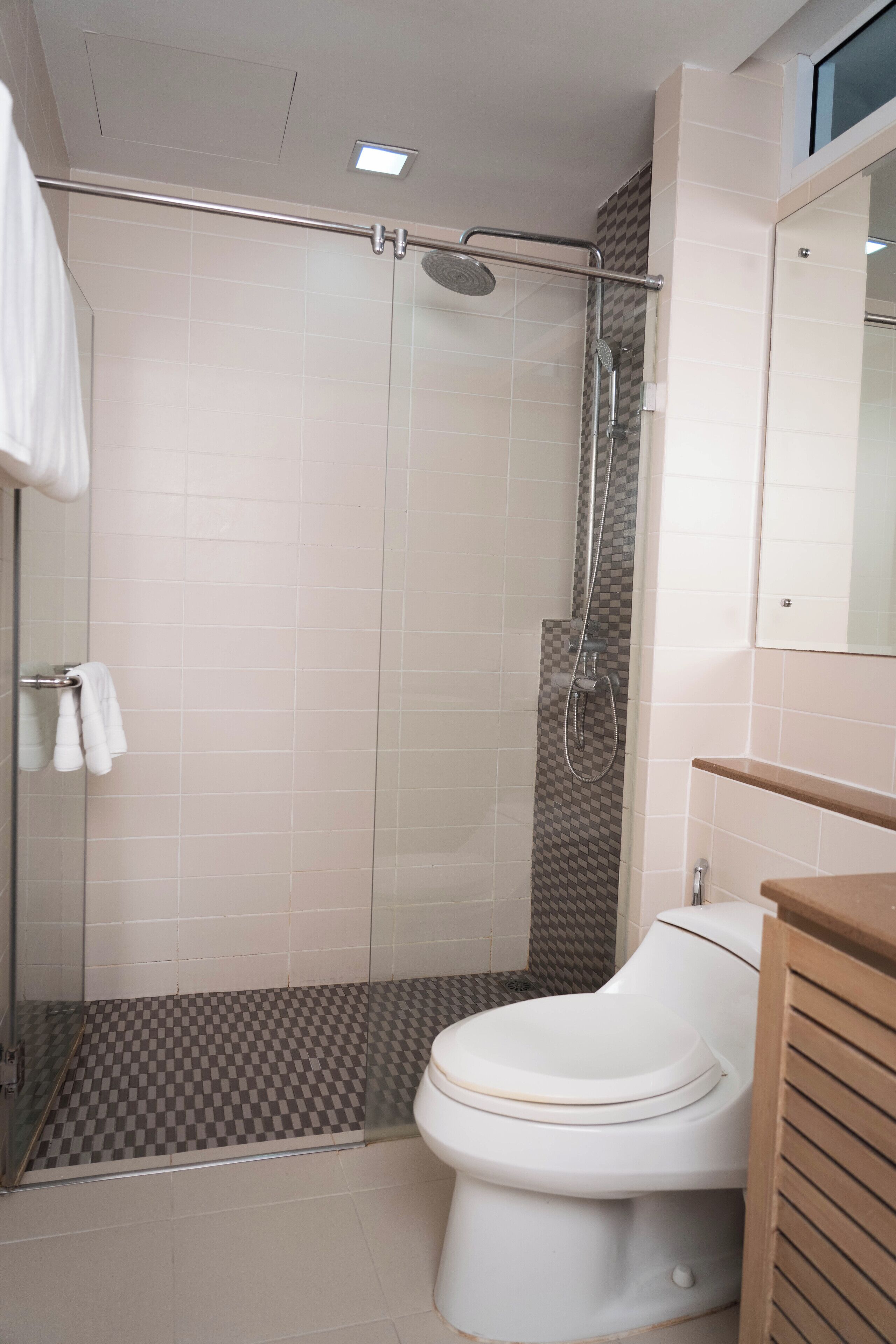 A bathroom with a glass-enclosed shower, a toilet, and a wooden vanity.