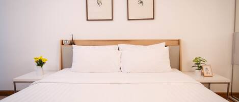 A neatly made bed with white linens, a wooden headboard, and two framed pictures on the wall.