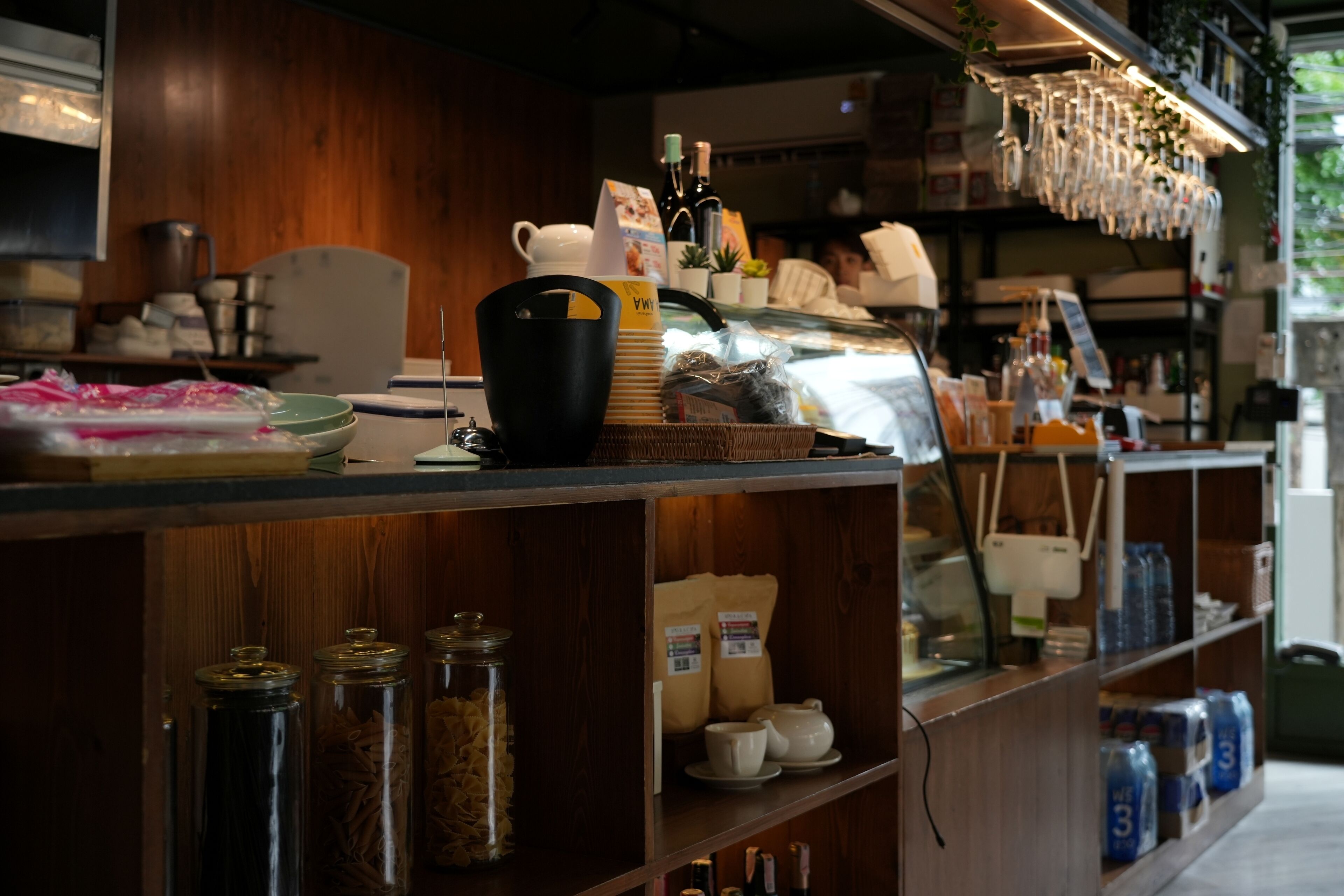 Zona de bar con estantes llenos de botellas, frascos y utensilios de cocina.
